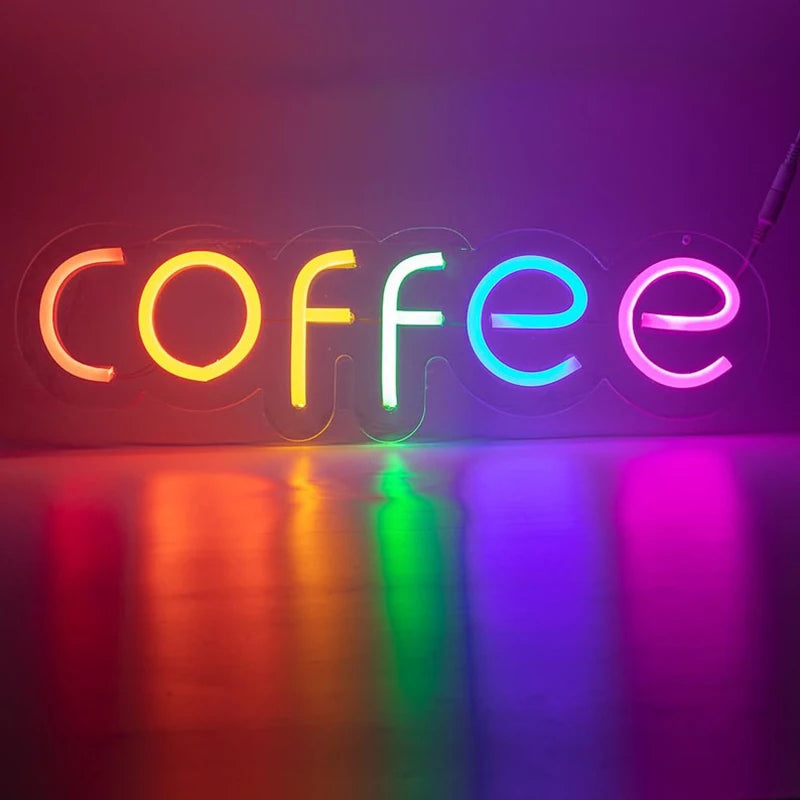 Letrero LED de neón con texto “coffee” multicolor sobre pared oscura.