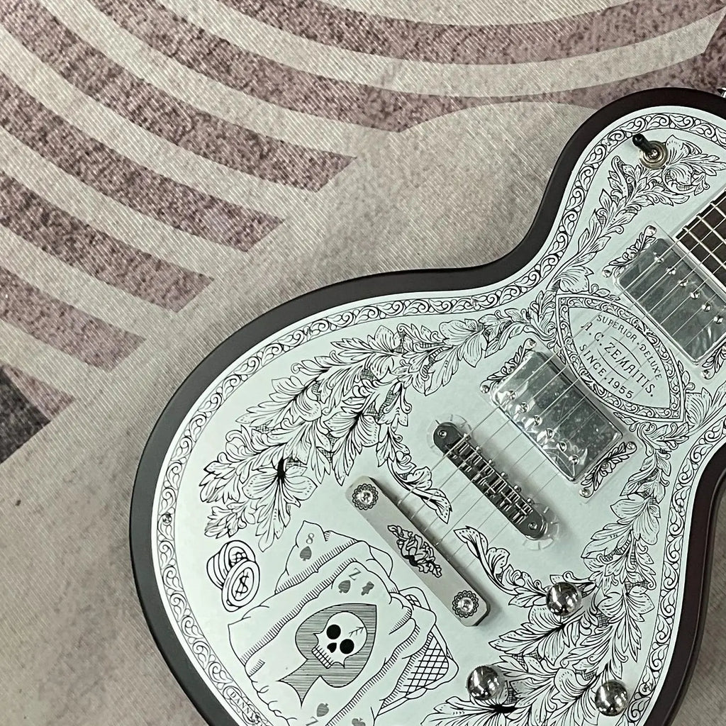 Guitarra eléctrica con tapa de aluminio grabado, cuerpo de caoba, incrustaciones de ébano en la tapa, doble sistema de pastillas humbucker, puente fijo cromado, 22 trastes.