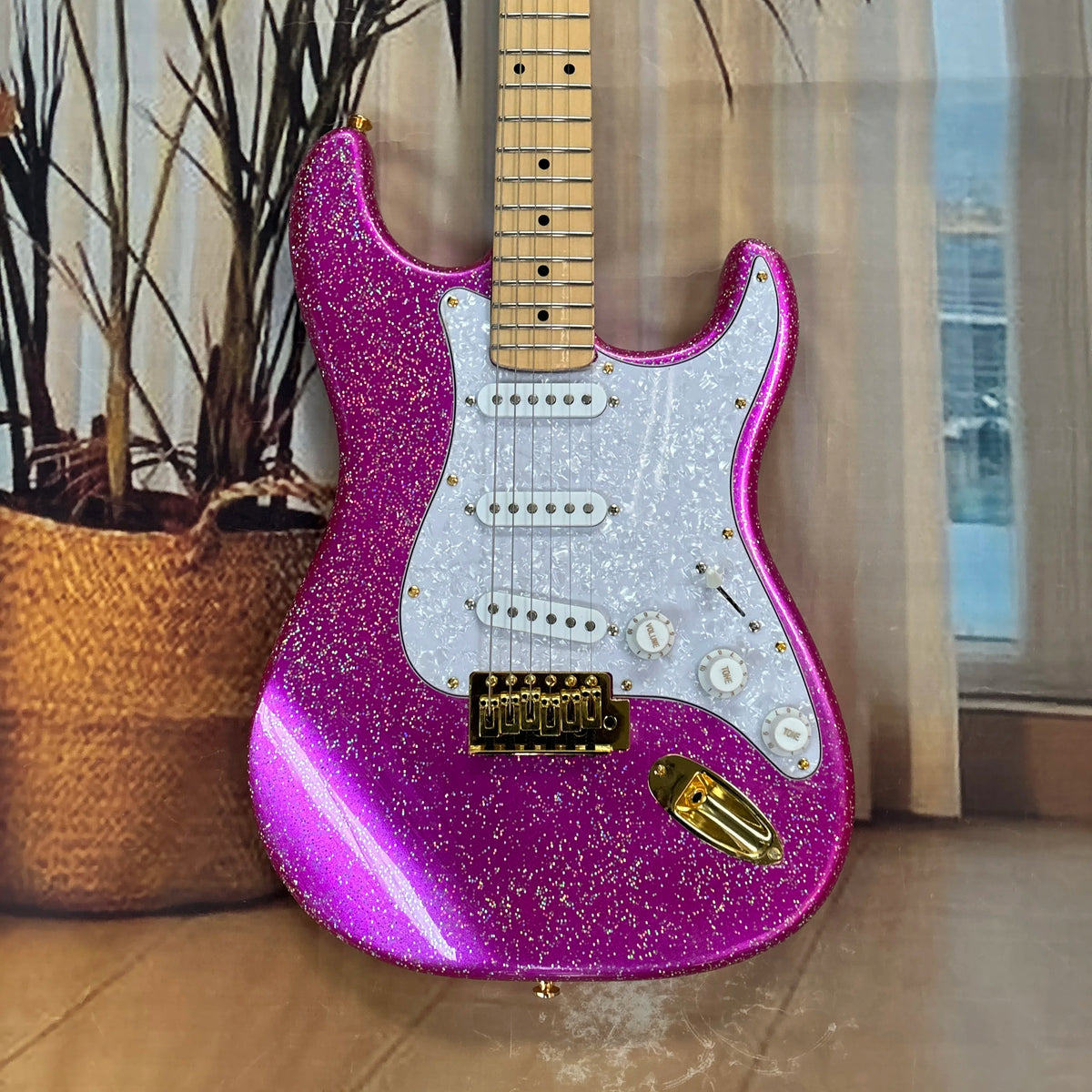 Guitarra eléctrica de 6 cuerdas de color rosa con granos grandes, pickguard blanco y herrajes dorados, guitarra con pastillas SSS brillantes y transparentes.
