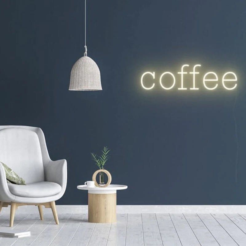 Letrero de neón “coffee” con luz blanca cálida en pared gris
