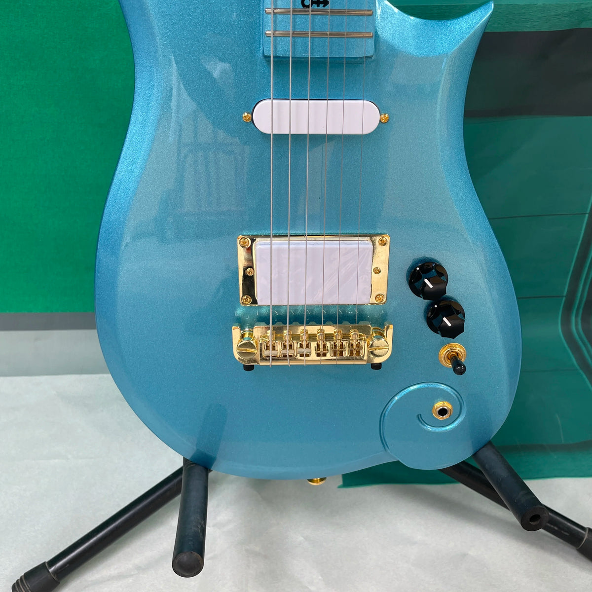 Guitarra eléctrica de 6 cuerdas, un cuerpo único en forma de nube asimétrica y herrajes dorados, una guitarra inusual y distintiva.