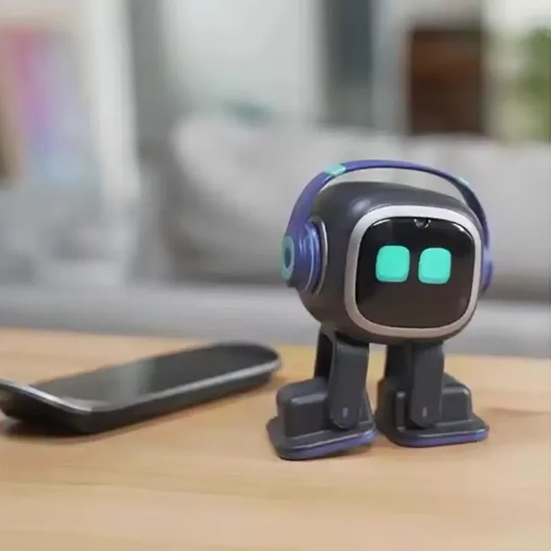 Robot EMO negro sobre mesa con manos abatibles y ojos LED verdes