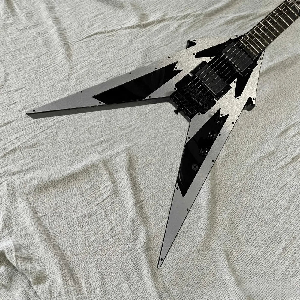 Guitarra eléctrica con forma de V, diseño geométrico en color plateado y negro, placa frontal de aluminio, puente con sistema de trémolo, pastillas HH, herrajes negros.