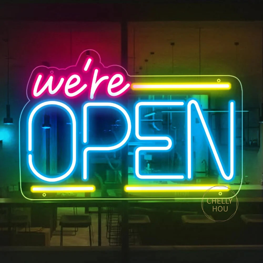 Letrero de neón LED “We’re OPEN” con contorno azul y amarillo, sobre placa transparente