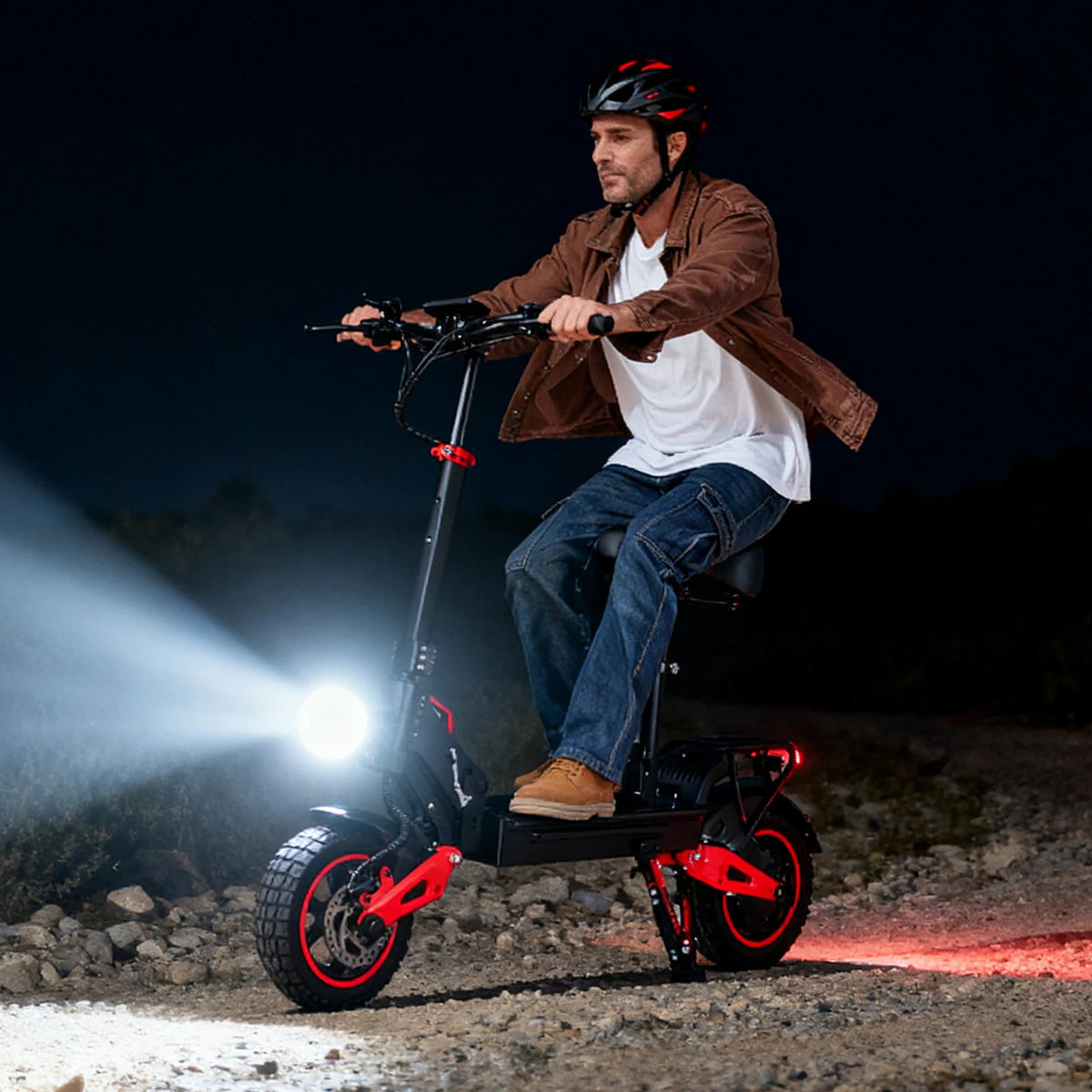 Patinete eléctrico rojo con luces delanteras y neumáticos grandes, sobre terreno rocoso