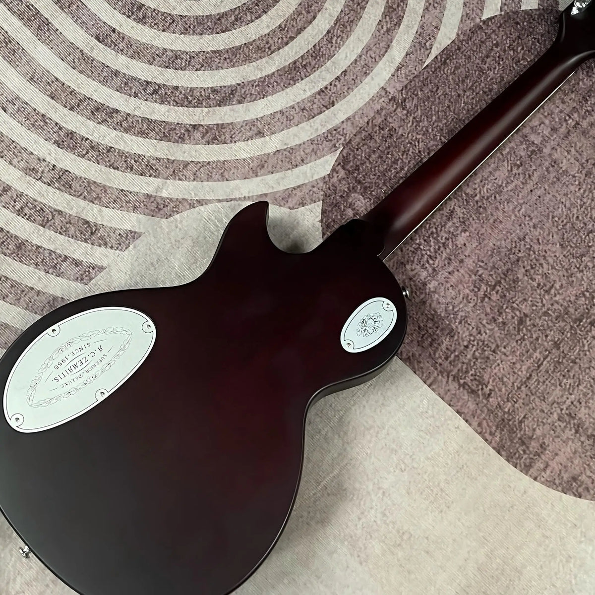 Guitarra eléctrica con tapa de aluminio grabado, cuerpo de caoba, incrustaciones de ébano en la tapa, doble sistema de pastillas humbucker, puente fijo cromado, 22 trastes.