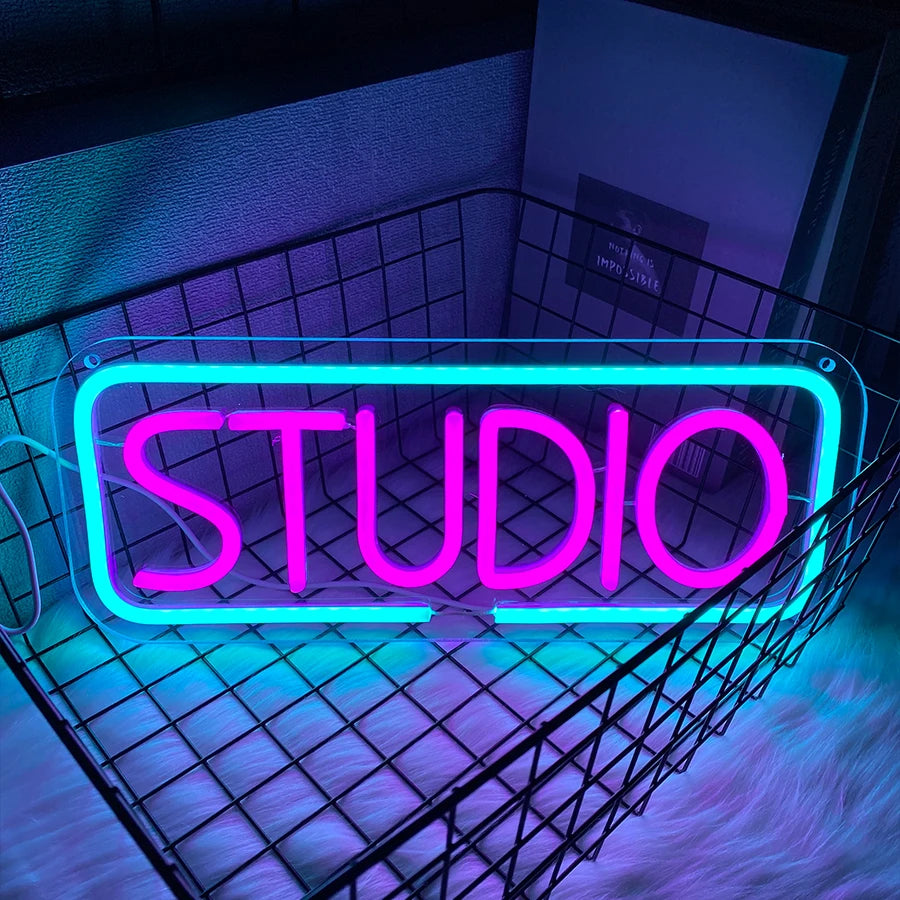 Cartel de neón LED "STUDIO" en letras magenta con borde azul