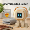 Robot de escritorio beige con auriculares y pantalla azul, junto a cuaderno y bolígrafo.