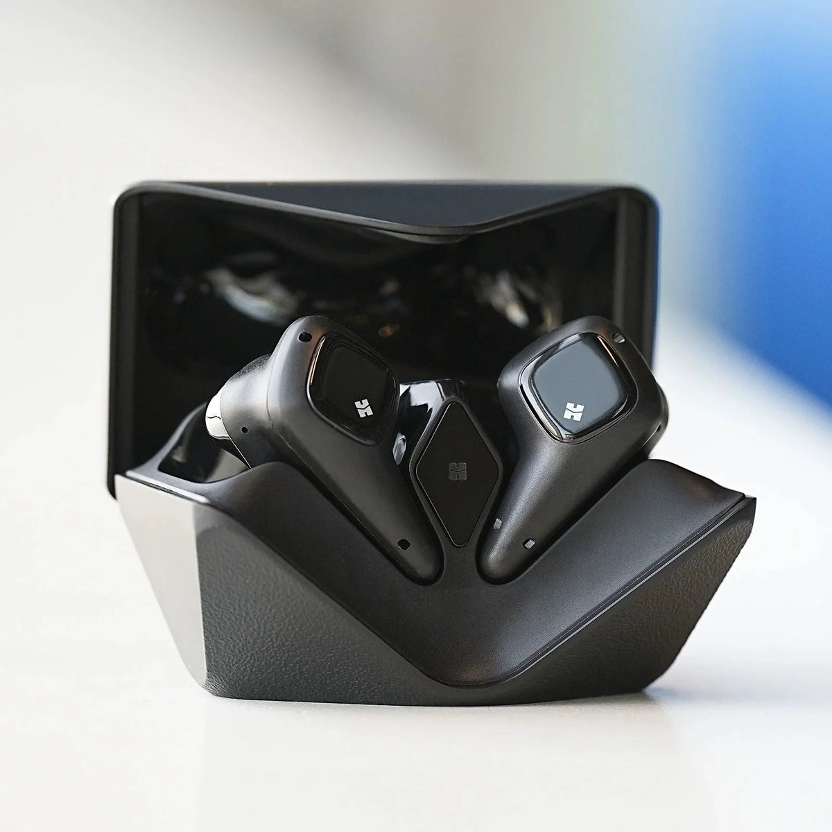 Auriculares inalámbricos negros en estuche de carga abierto, vista frontal