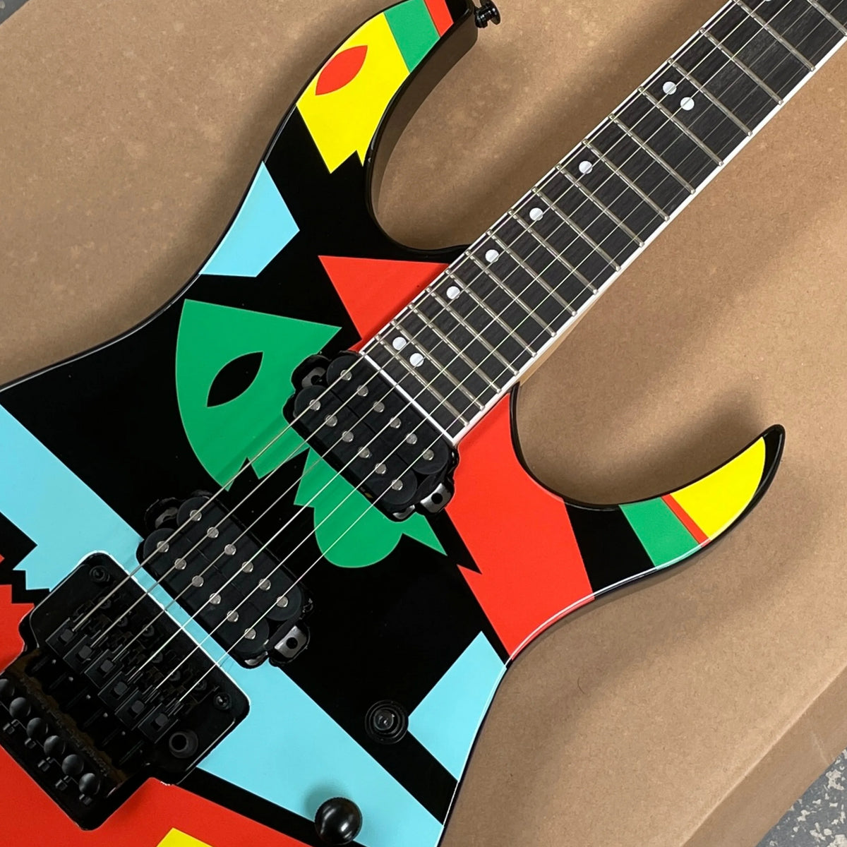 Guitarra eléctrica de 6 cuerdas con un moderno acabado de grafiti geométrico y pastillas HH, ideal para entusiastas del rock avanzado.