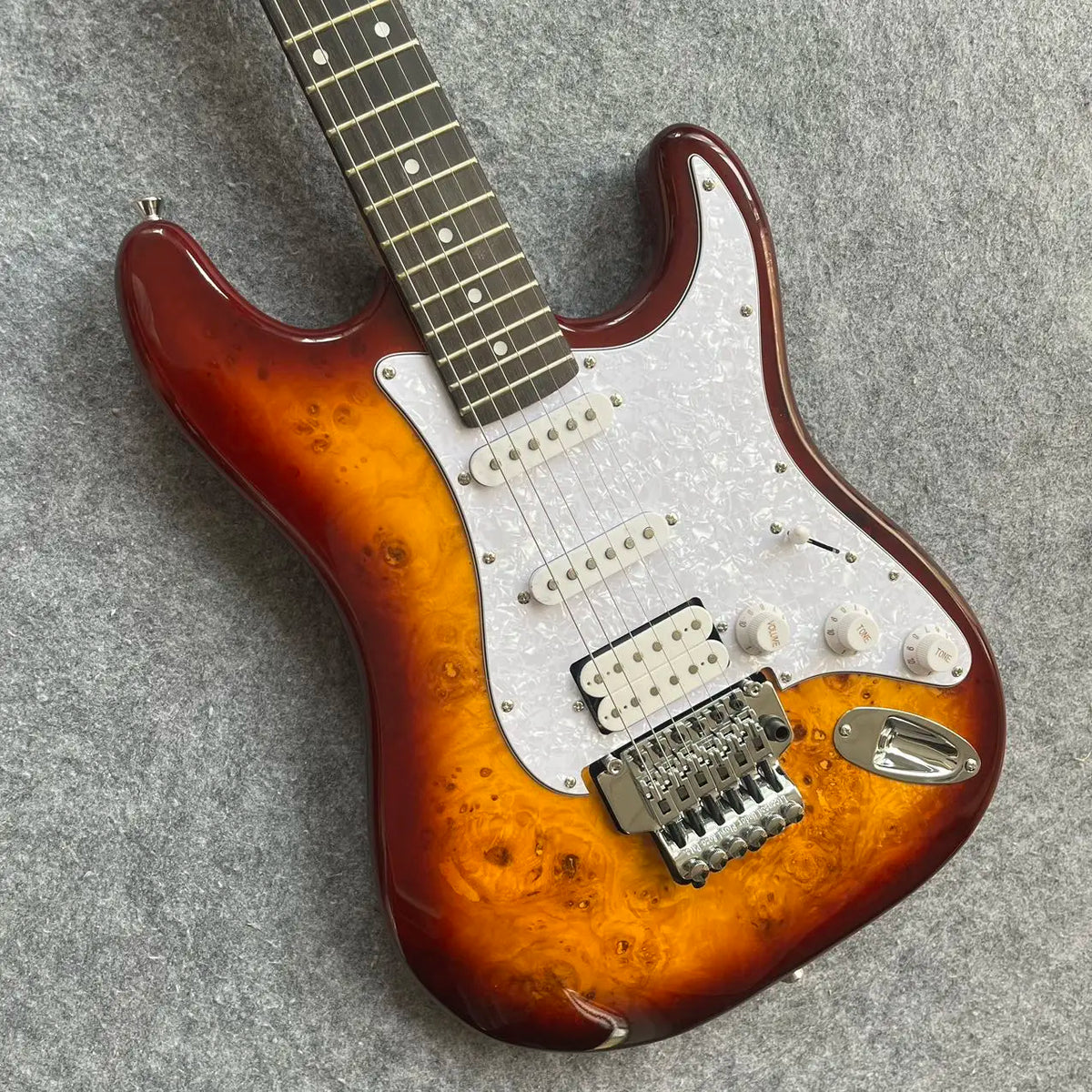 Guitarra de alta calidad con acabado Sunburst, incrustaciones de estrellas, sistema de trémolo y pastillas SSH 2026