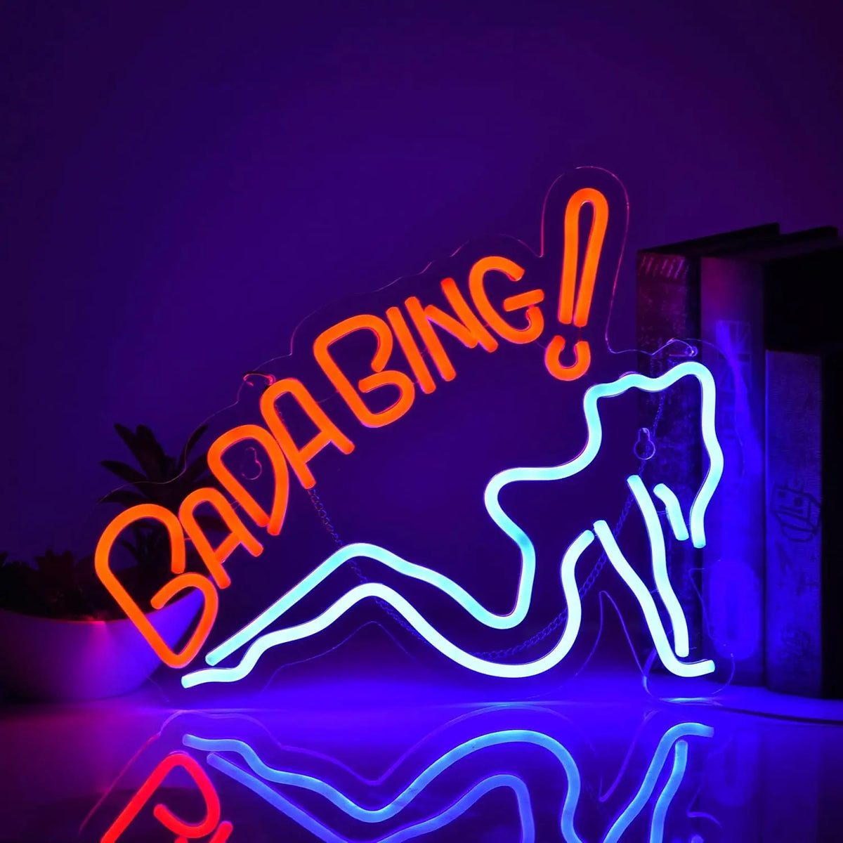 Letrero luminoso neón “Bada Bing!” naranja con efecto arco y silueta azul