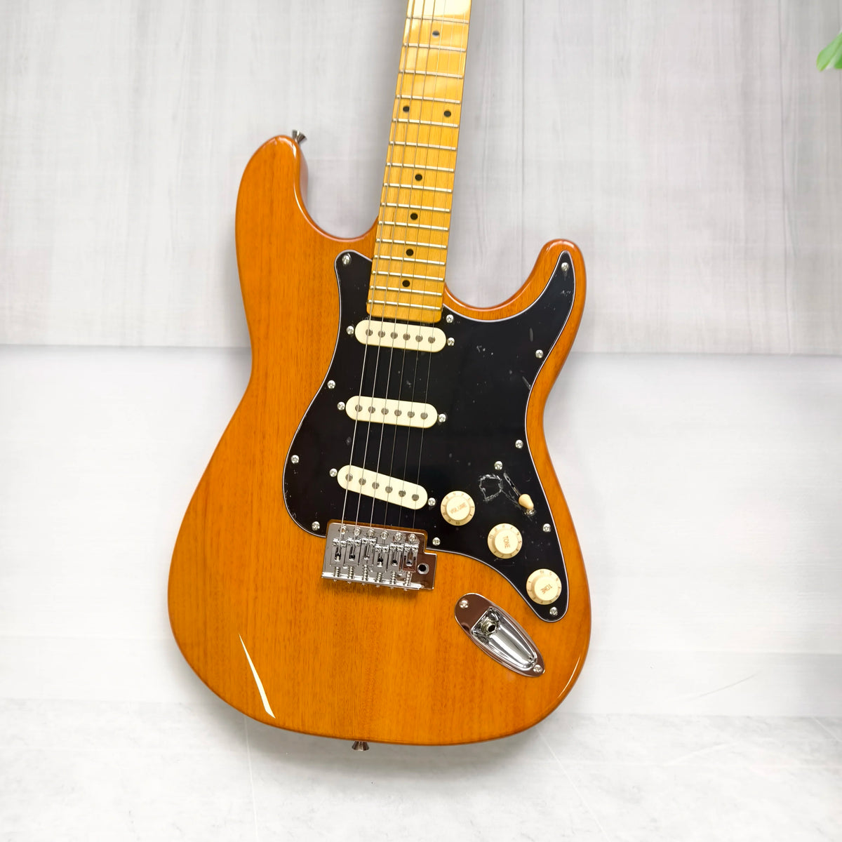 Guitarra eléctrica de madera natural con diapasón de arce, guardapalos negro SSS, bobina y trémolo. En stock.