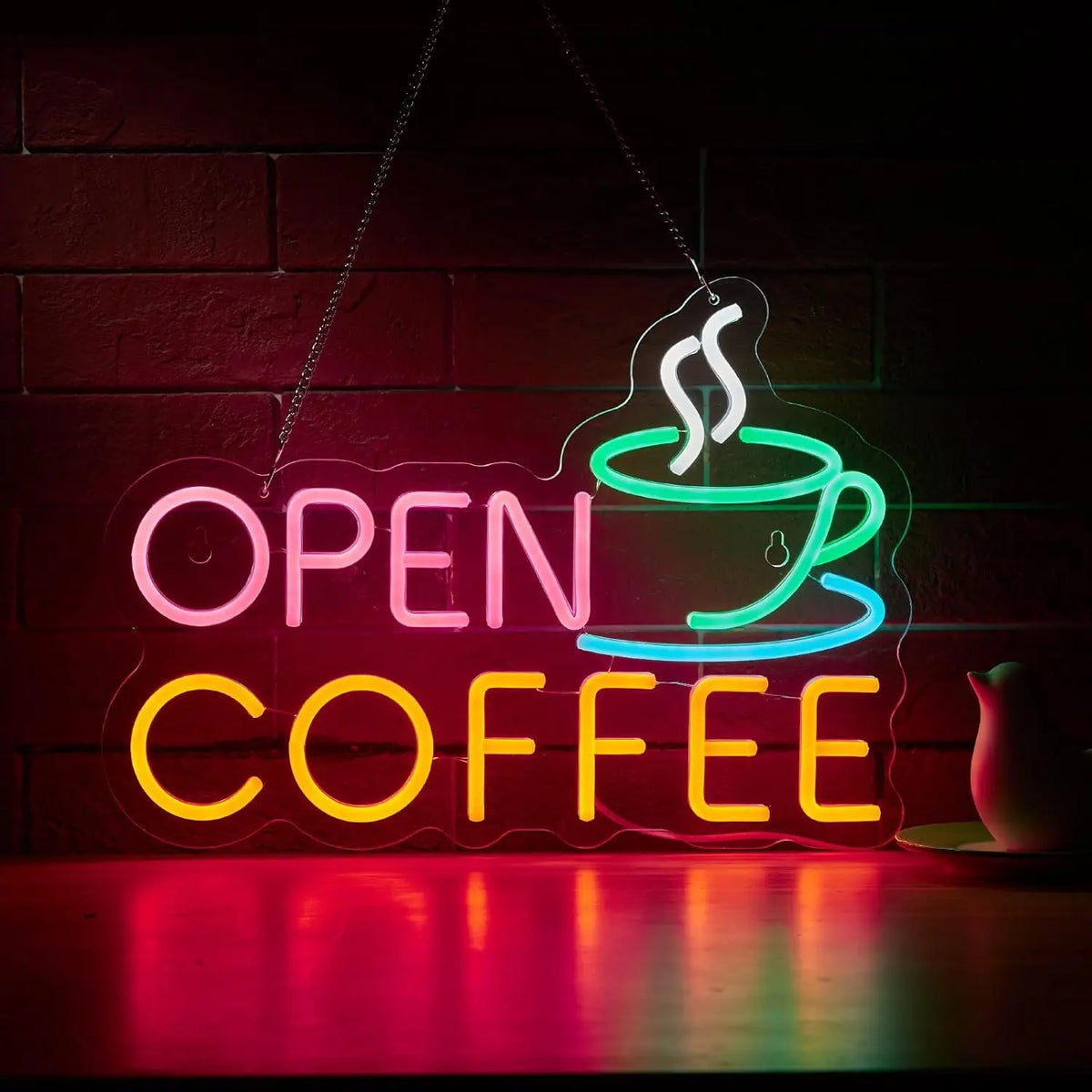 Cartel neón “OPEN COFFEE” con taza, luces LED de colores sobre pared oscura.