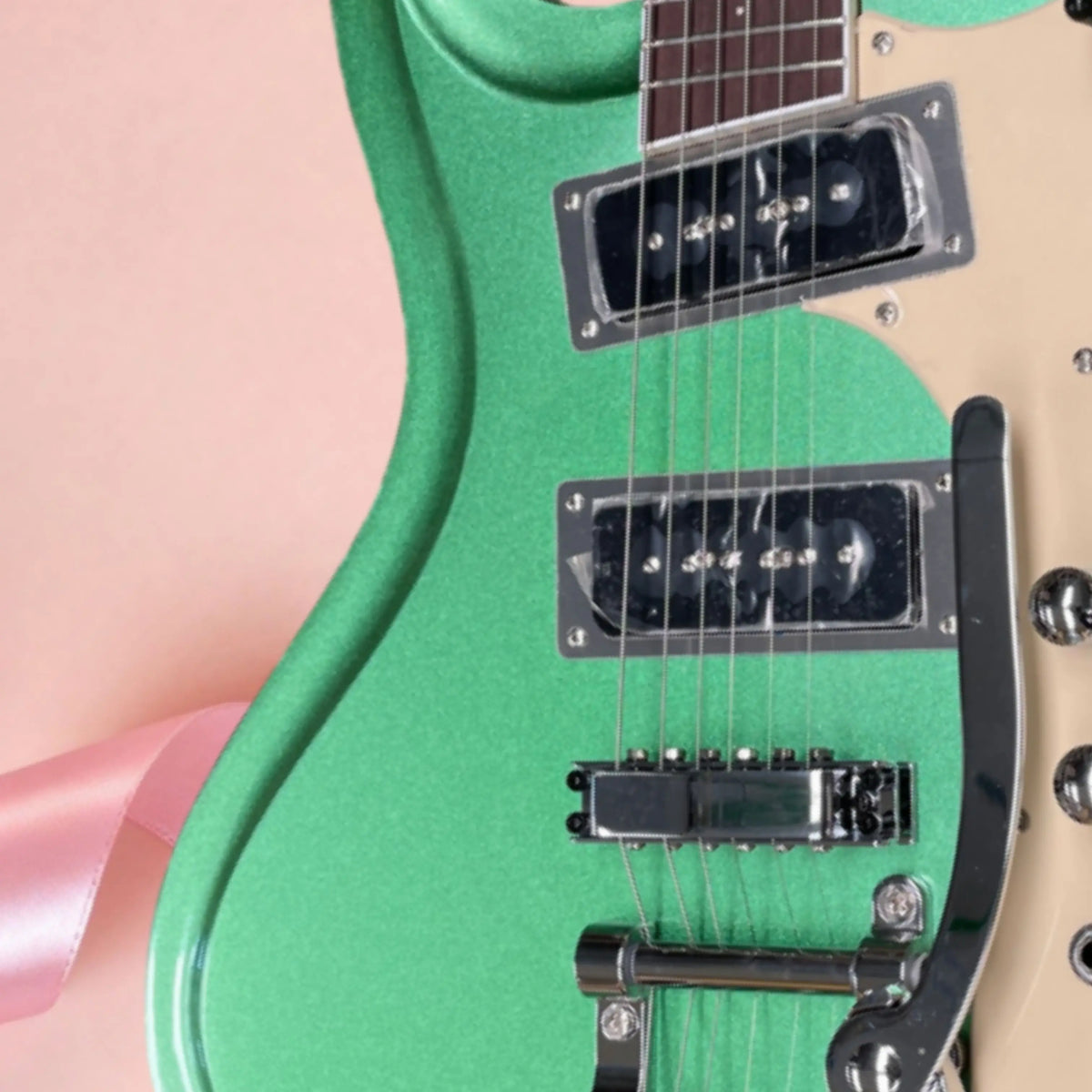Guitarra eléctrica de 6 cuerdas, de color verde metálico, con herrajes plateados y placa protectora de color beige. Ideal para principiantes.