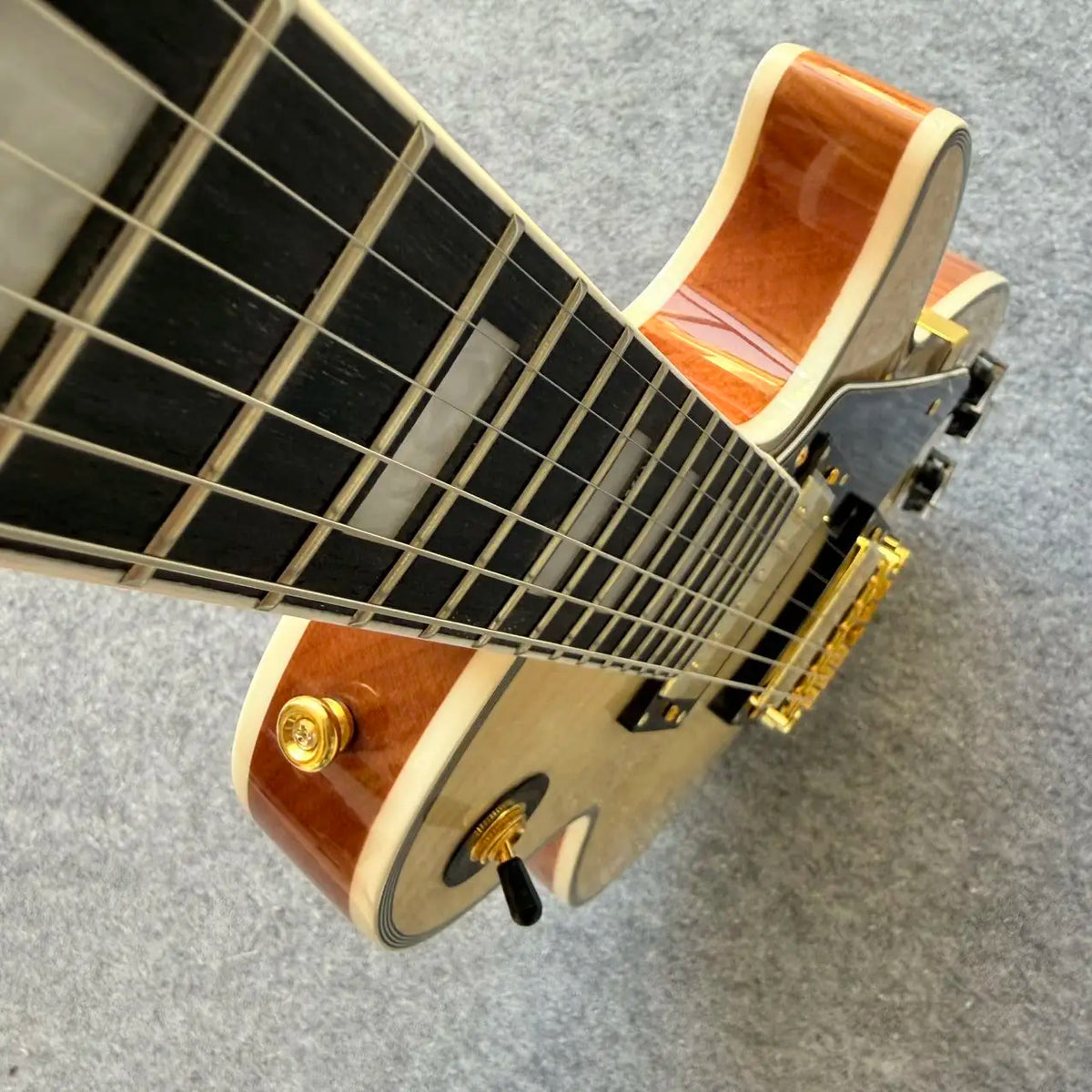 Guitarra eléctrica de cuerpo sólido, con tapa de arce flameado natural, herrajes dorados y doble pastilla humbucker, 22 trastes, ideal para principiantes.