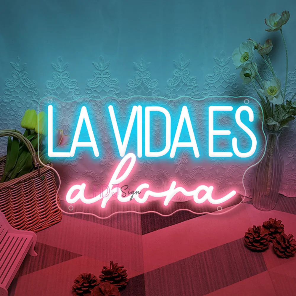 Letrero LED “LA VIDA ES ahora” con letras azul claro y contorno rosado