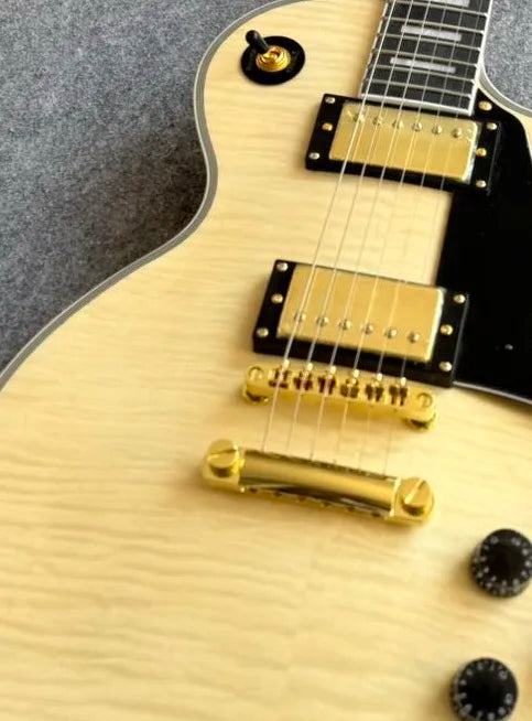 Guitarra eléctrica de cuerpo sólido, con tapa de arce flameado natural, herrajes dorados y doble pastilla humbucker, 22 trastes, ideal para principiantes.