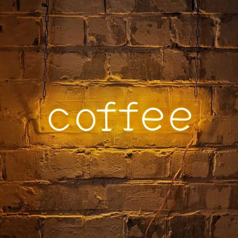 Letrero de neón “coffee” con luz blanca cálida sobre pared de ladrillo