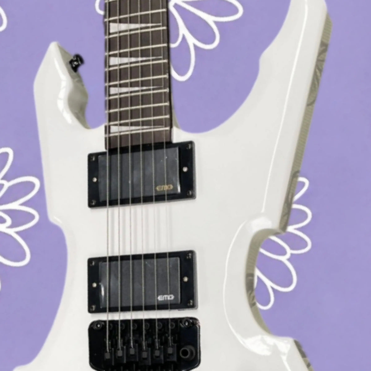 Guitarra eléctrica de color blanco puro con forma irregular, acabado de alto brillo, herrajes negros, ideal para actuaciones en escenarios de heavy metal.