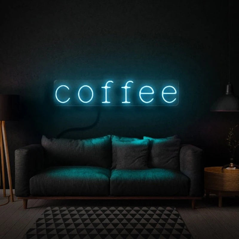 Letrero LED de neón con texto “coffee” en luz turquesa sobre pared oscura.
